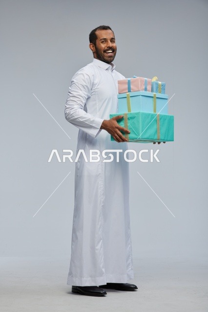 رجل سعودي يحمل صناديق هدايا مغلفة في الاستوديو
