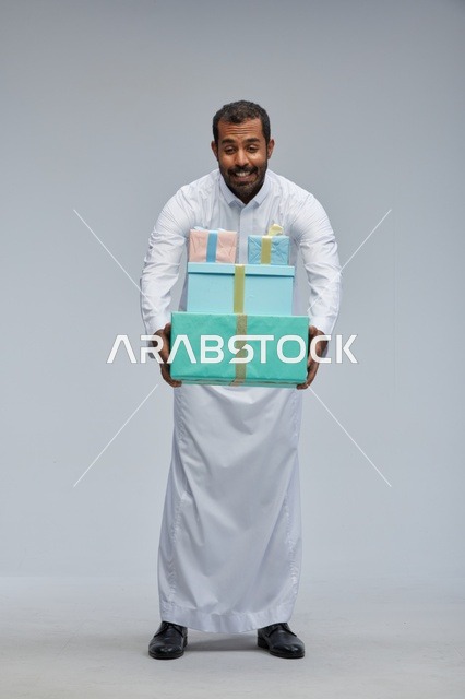 رجل سعودي بالزي التقليدي يحمل صناديق هدايا ملونة