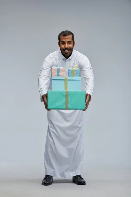 رجل سعودي بالزي التقليدي يحمل صناديق هدايا ملونة