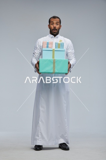 رجل سعودي مندهش يحمل صناديق هدايا مغلفة بالثوب