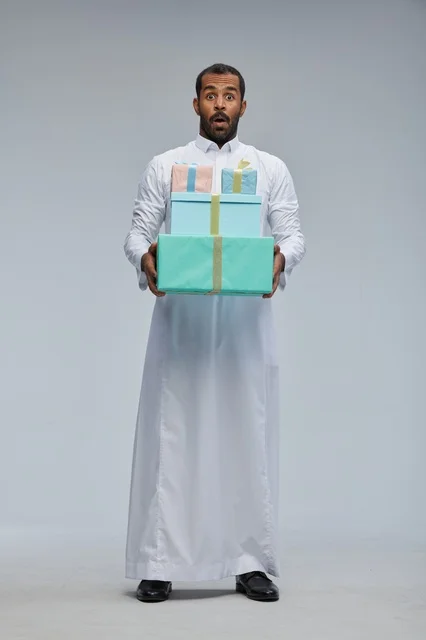 رجل سعودي مندهش يحمل صناديق هدايا مغلفة بالثوب