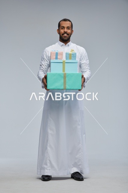 رجل سعودي بالثوب التقليدي يحمل صناديق هدايا ملونة