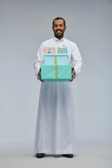 رجل سعودي بالزي التقليدي يحمل صناديق هدايا ملونة