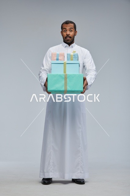 رجل سعودي يحمل صناديق هدايا بملامح وجه مفاجأة