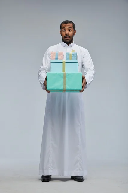 رجل سعودي يحمل صناديق هدايا بملامح وجه مفاجأة
