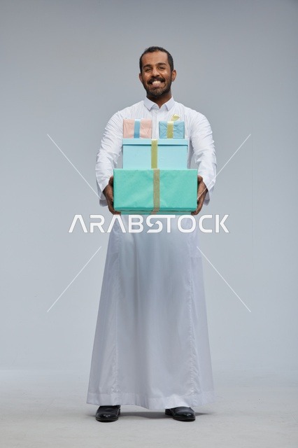 رجل سعودي بالزي التقليدي يحمل صناديق هدايا