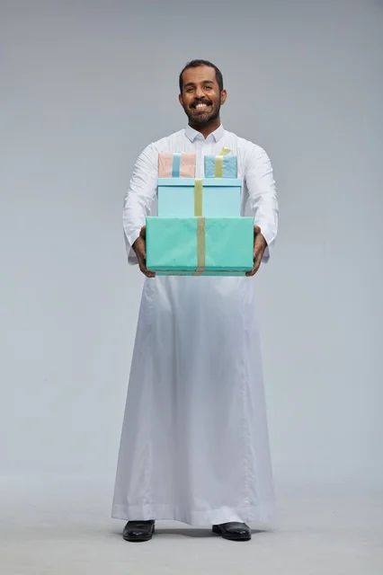 رجل سعودي بالزي التقليدي يحمل صناديق هدايا