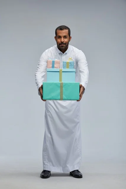 رجل سعودي بالزي التقليدي يحمل صناديق هدايا ملونة
