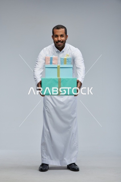 رجل سعودي يرتدي الثوب يحمل صناديق هدايا مغلفة