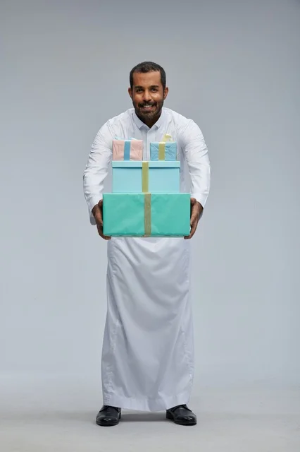 رجل سعودي يرتدي الثوب يحمل صناديق هدايا مغلفة