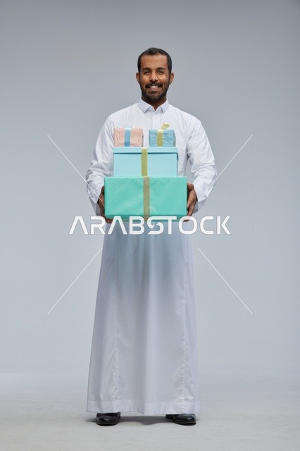 رجل سعودي بالزي التقليدي يحمل صناديق هدايا ملونة