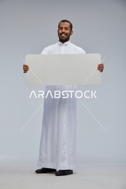 رجل سعودي بالثوب التقليدي يحمل لوحة بيضاء فارغة