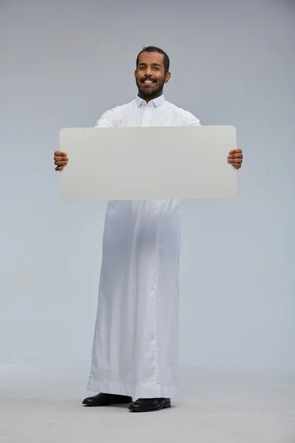 رجل سعودي بالثوب التقليدي يحمل لوحة بيضاء فارغة