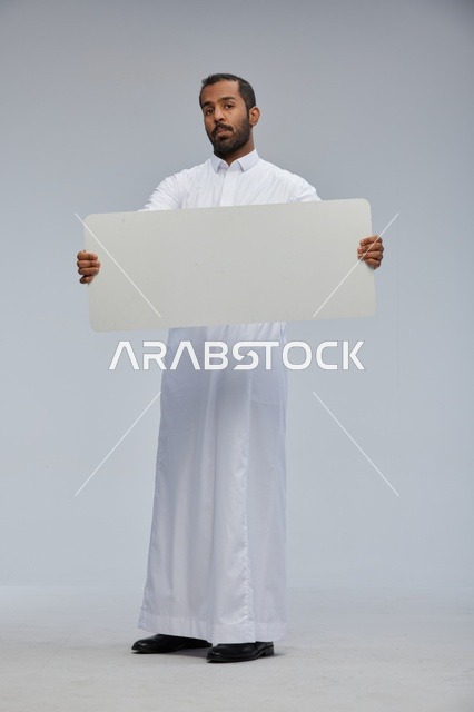 رجل سعودي بالثوب يحمل لوحة بيضاء فارغة للإعلانات