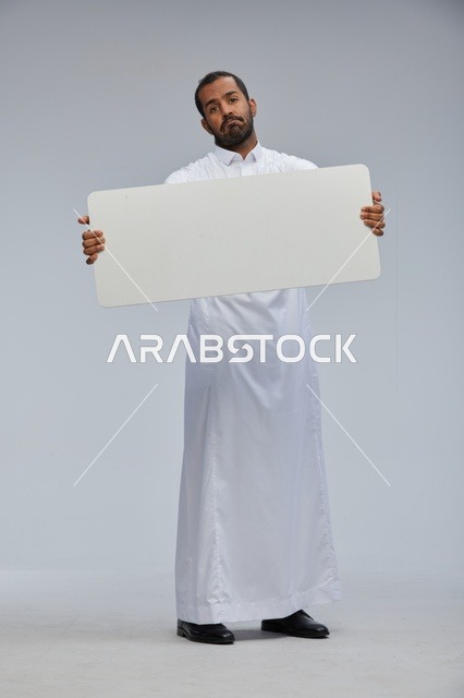 رجل سعودي بالثوب التقليدي يحمل لوحة بيضاء فارغة