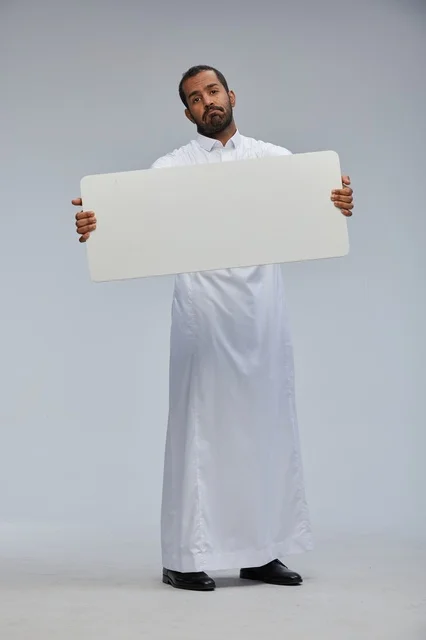 رجل سعودي بالثوب التقليدي يحمل لوحة بيضاء فارغة