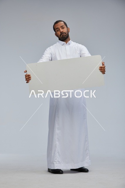 رجل سعودي بالزي التقليدي يحمل لوحة بيضاء فارغة