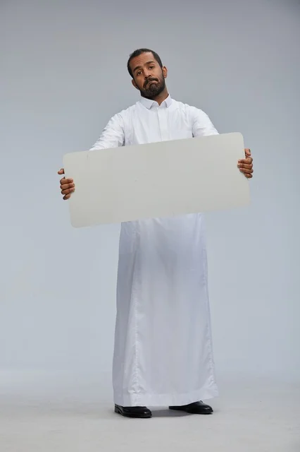 رجل سعودي بالزي التقليدي يحمل لوحة بيضاء فارغة
