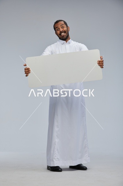 رجل سعودي بالثوب التقليدي يحمل لوحة بيضاء فارغة