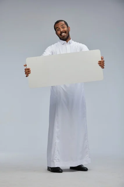 رجل سعودي بالثوب التقليدي يحمل لوحة بيضاء فارغة