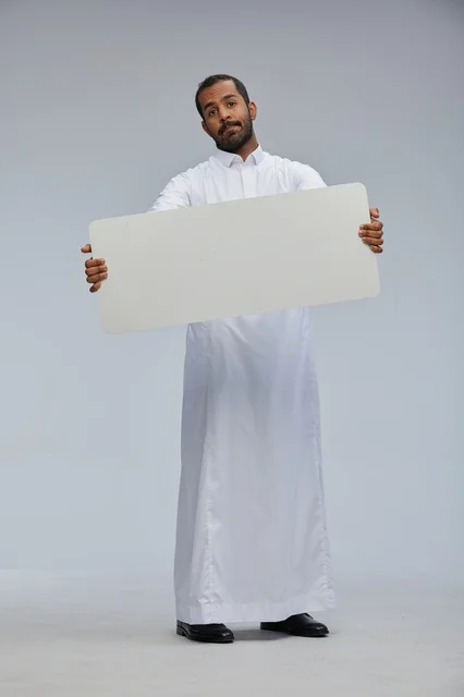 رجل سعودي بالزي التقليدي يحمل لوحة بيضاء فارغة