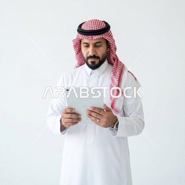 رجل أعمال سعودي يستخدم جهاز لوحي بخلفية بيضاء