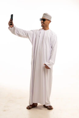 رجل عماني بالزي التقليدي يلتقط صورة سيلفي