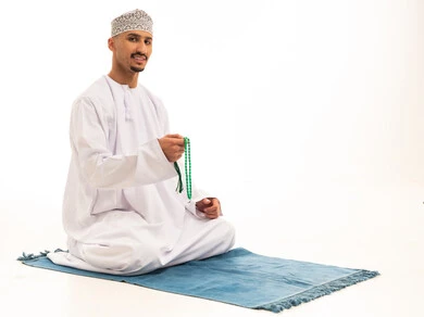Omani Man in Traditional Clothing Sitting on Prayer Mat