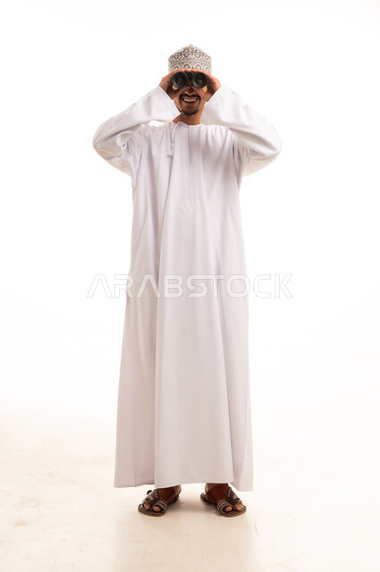 رجل عماني بالزي التقليدي يستخدم المنظار