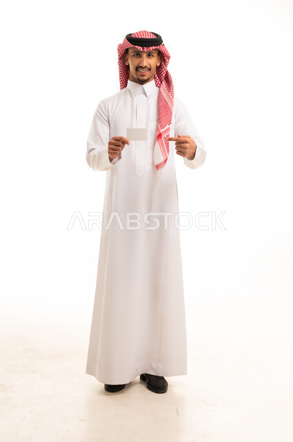 رجل سعودي يحمل بطاقة بيضاء فارغة في استوديو