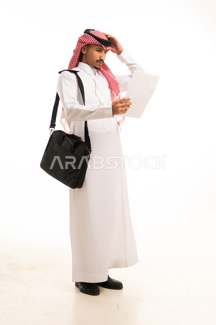 رجل سعودي بالثوب التقليدي حائر يحمل ورقة في استوديو