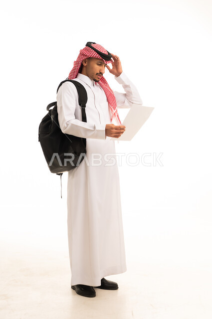 رجل سعودي بالزي التقليدي يحمل ورقة مع حقيبة ظهر