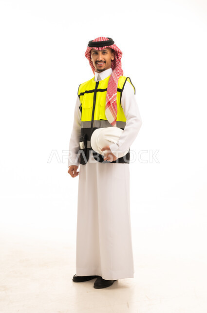 مهندس سعودي يرتدي سترة السلامة ويحمل خوذة العمل