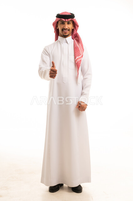 رجل سعودي بالثوب التقليدي يشير بعلامة الإعجاب والنجاح