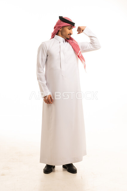 رجل سعودي بالثوب التقليدي يستعرض قوة عضلاته