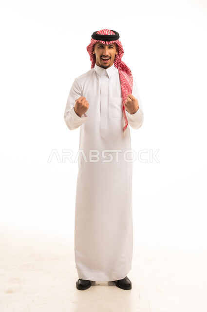 رجل سعودي متحمس يحتفل بالنجاح والإنجاز بالثوب التقليدي