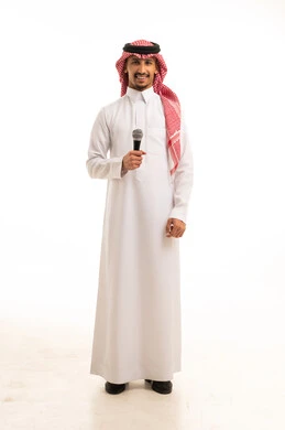 رجل سعودي بالزي التقليدي يمسك ميكروفون في استوديو
