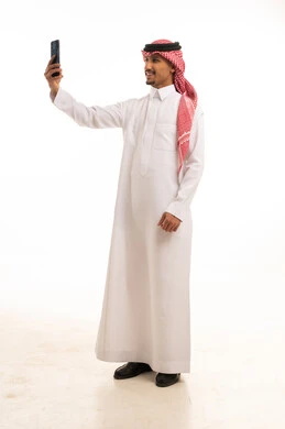 Saudi Man in Traditional Thobe Using Smartphone