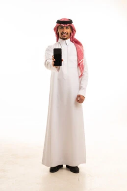 رجل سعودي بالزي التقليدي يمسك هاتف ذكي بخلفية بيضاء