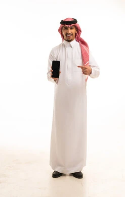 رجل سعودي بالزي التقليدي يشير إلى هاتف ذكي