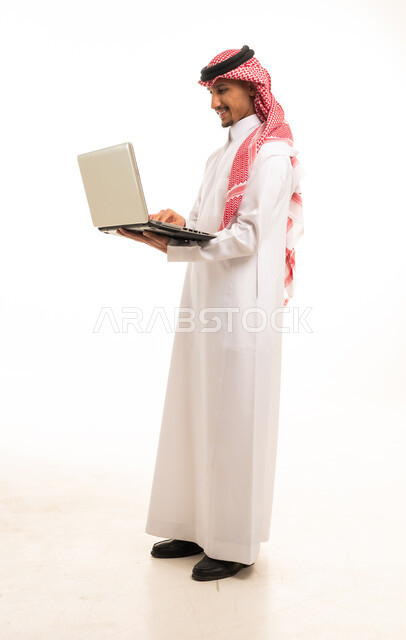 رجل سعودي يستخدم اللابتوب على خلفية بيضاء