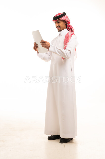 Saudi Man in Traditional Thobe Reading Document