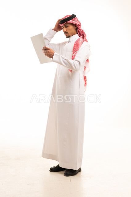Saudi Man in Traditional Thobe Reading White Document