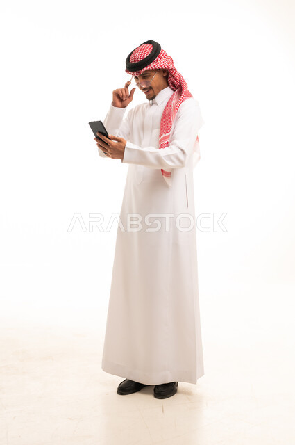 رجل سعودي بالزي التقليدي يستخدم الهاتف الذكي