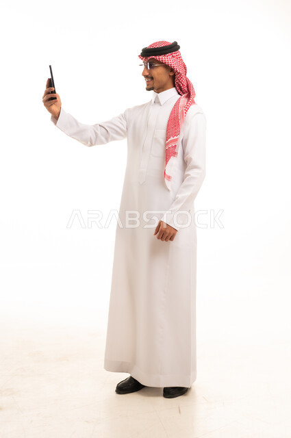 رجل سعودي باللباس التقليدي يستخدم الهاتف الذكي