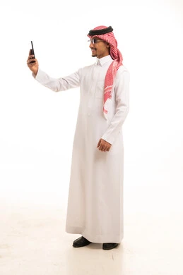 رجل سعودي باللباس التقليدي يستخدم الهاتف الذكي