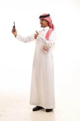 رجل سعودي بالثوب التقليدي يستخدم الهاتف الذكي