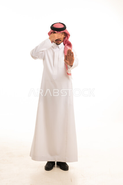 رجل سعودي يرتدي الثوب التقليدي ويقوم بإيماءة التوقف