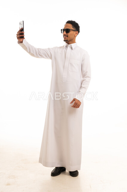 رجل سعودي بالثوب الأبيض يلتقط صورة سيلفي في استوديو