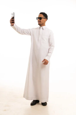 رجل سعودي بالثوب الأبيض يلتقط صورة سيلفي في استوديو